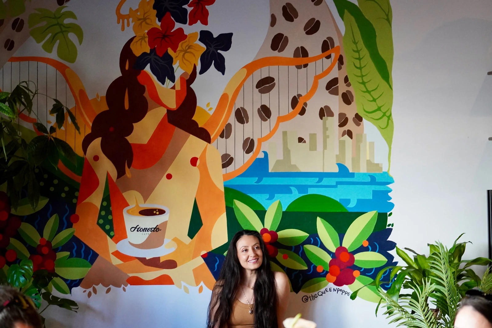 カラフルで大きな絵の前に座るSulmazさん